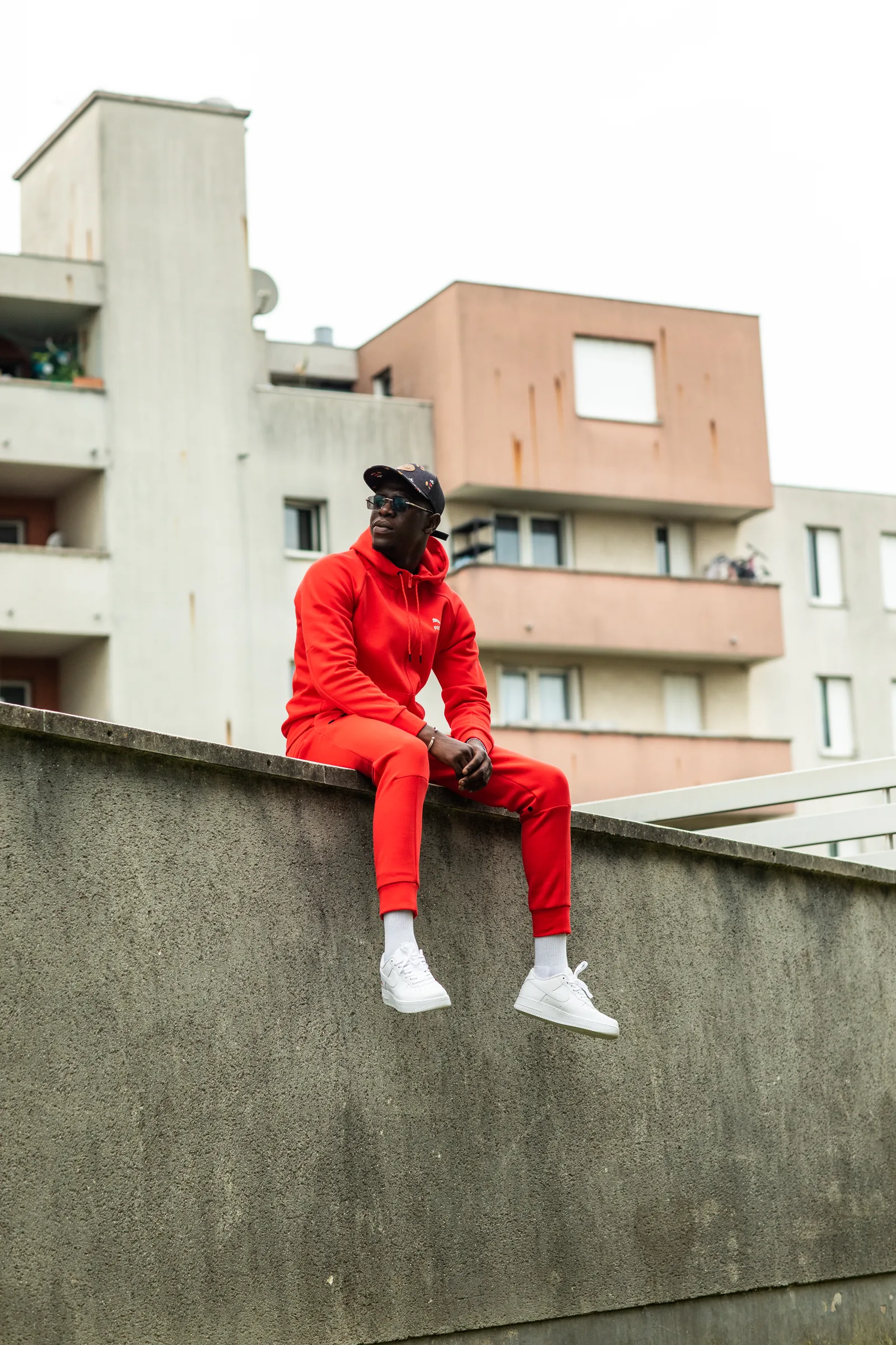 Pico en survêtement rouge assis sur un muret