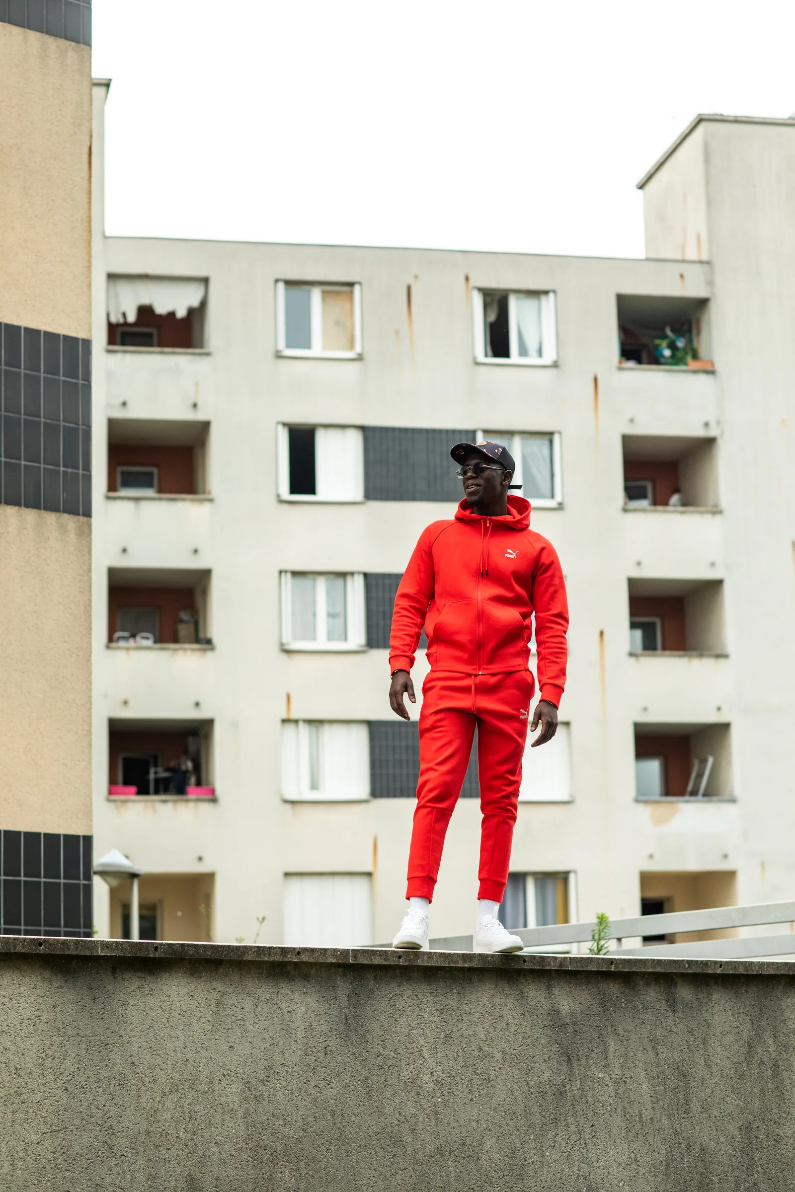 Pico en survêtement rouge au pied d’un immeuble